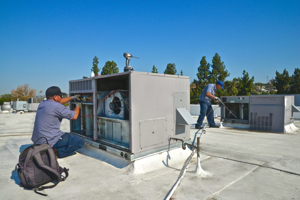2 ACS employees on a roof working on a cooling system